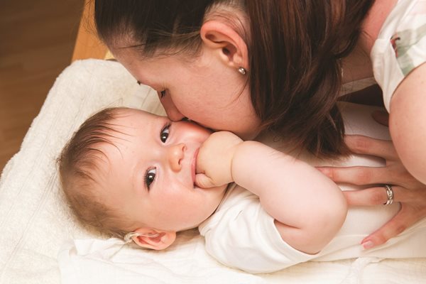mother holding her baby, both smiling and sharing a loving moment together