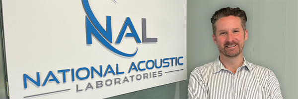 Matt, Research Audiologist at NAL, standing with NAL background