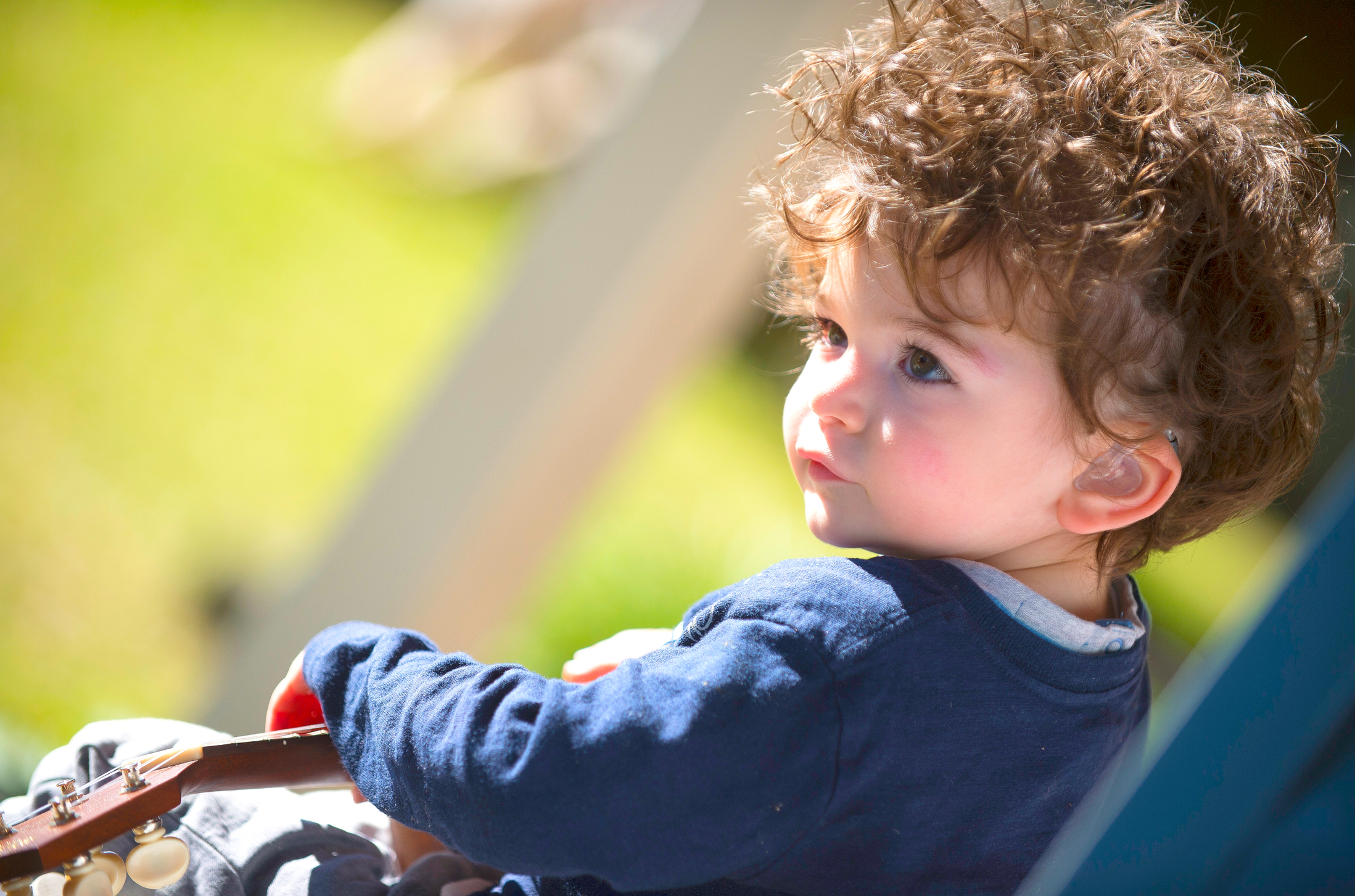 a baby with curly hair sitting in a stroller