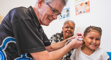 a man using an otoscope to check the ear of a girl