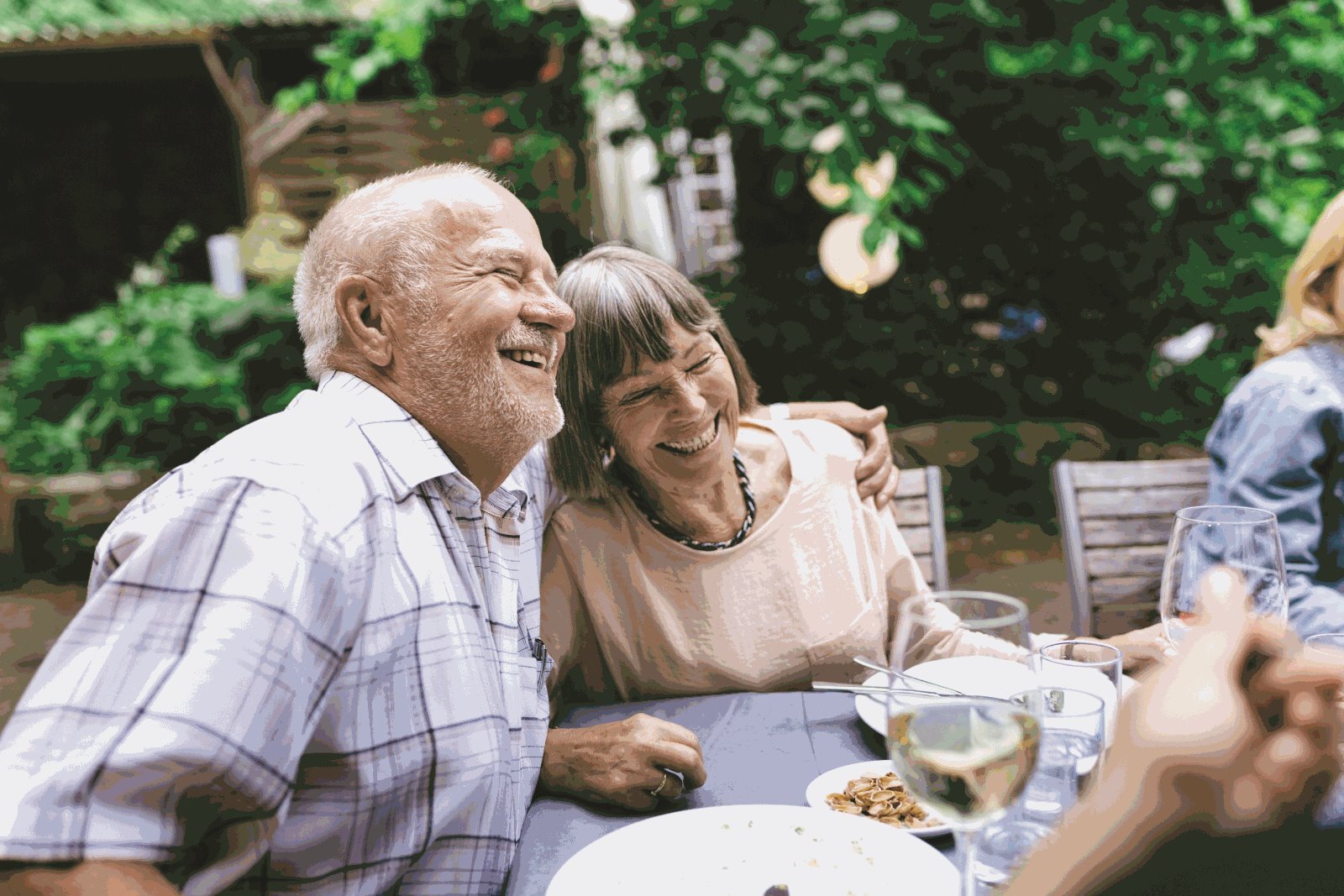 An elderly couple with one holding the other's shoulder and smiling