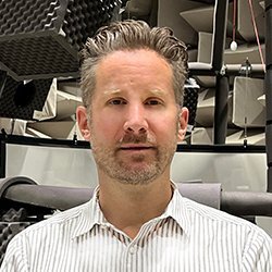 Matt, Research Audiologist at NAL, standing with NAL background