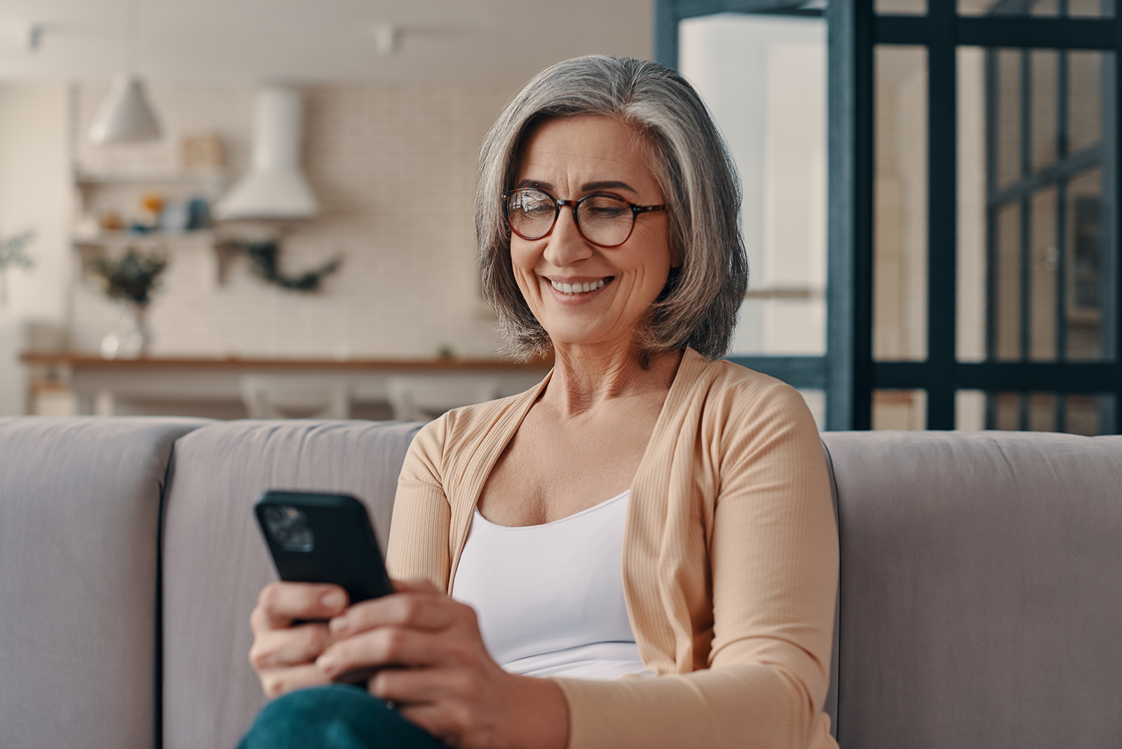 an elderly woman holding her mobile and smiling using the intelligent range hearing aids