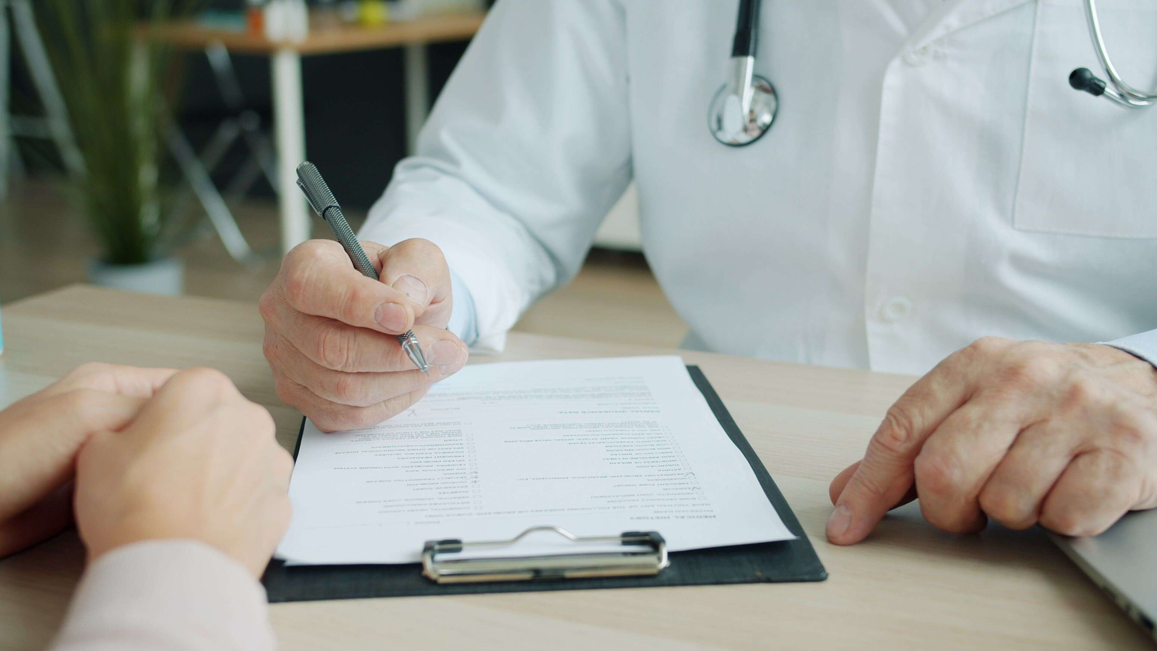 a doctor holding a pen over a clipboard