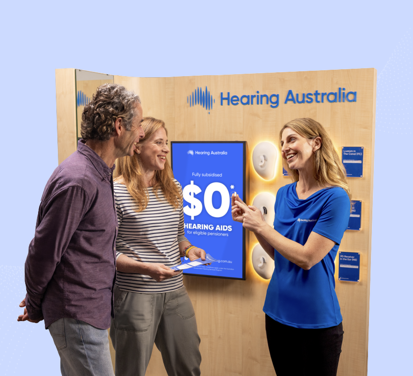 Hearing Australia centre staff member showing a hearing aid offer to a customer couple
