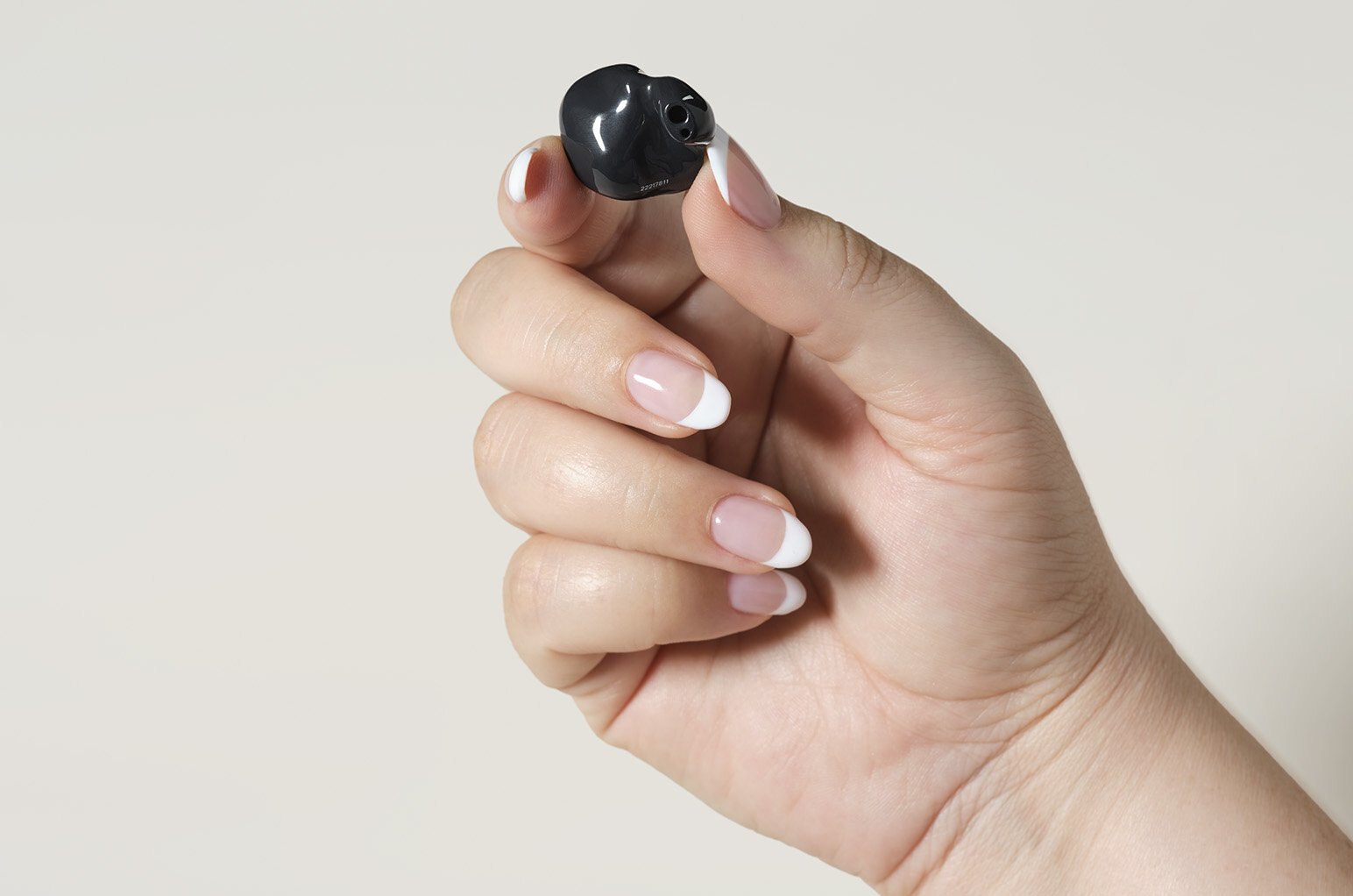 a hand holding a small hearing aid that sits in the canal