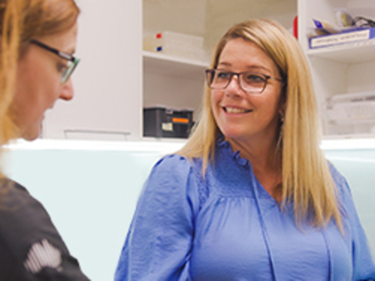 a woman in a blue shirt and glasses talking to a man