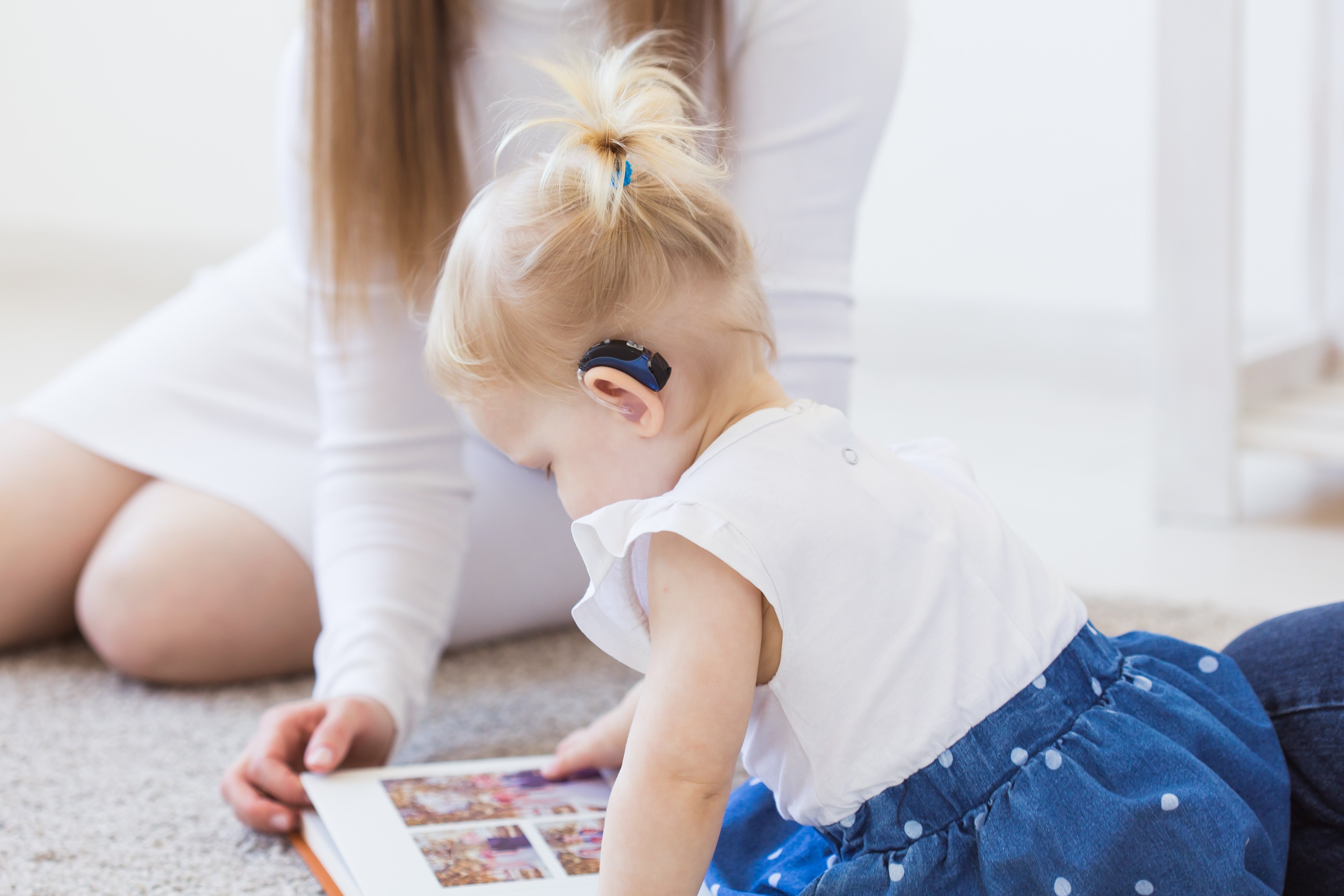 Baby with hearing aid browsing a book.