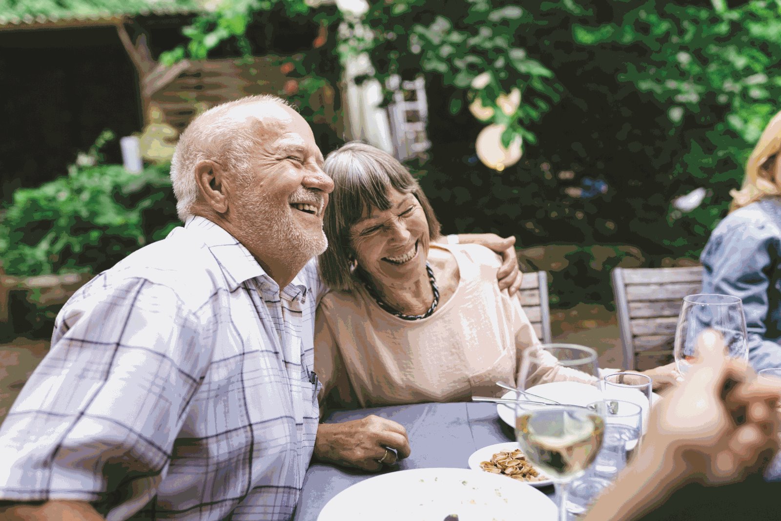 An elderly couple with one holding the other's shoulder and smiling