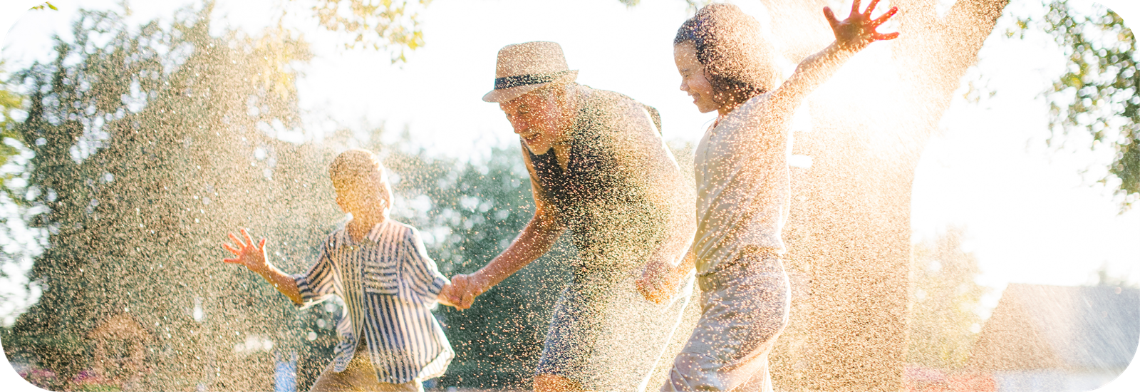 an elderly man holding his two young grandchildren, smiling and enjoying a loving moment together.